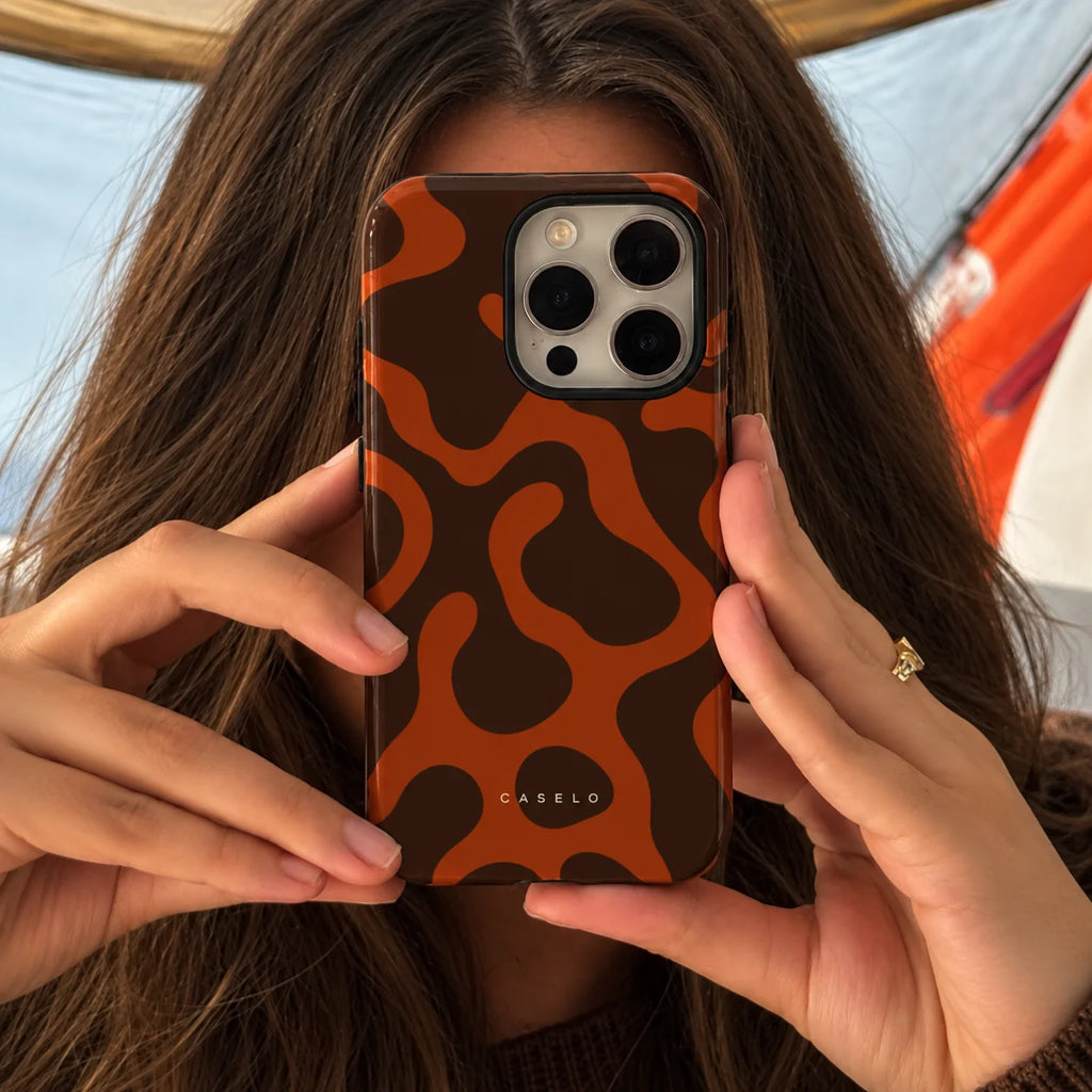 A person holding a smartphone with a brown and orange abstract wavy patterned phone case. The brand name 'CASELO' is printed in white near the bottom of the case.