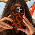 A person holding a smartphone with a brown and orange abstract wavy patterned phone case. The brand name 'CASELO' is printed in white near the bottom of the case.