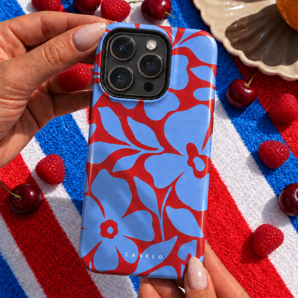 A hand holds a light blue and red floral patterned phone case on an iPhone. The case features a bold, repeating floral design with the brand name 'CASELO' printed near the bottom.